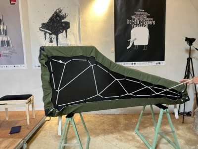 Préparation du clavecin avant le voyage vers la Haute Maurienne - ©ouille.allègre Un clavecin posé sur la tranche et avec sa housse.