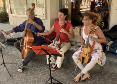 Le Consort Hexacorde fait une présentation sur la place de la Mairie de Bessans - ©ouille.allègre Christophe Oudin, Marjolaine Cambon et Valérie Beutin jouent de la viole de gambe sur la place extérieure de la mairie de Bessans.